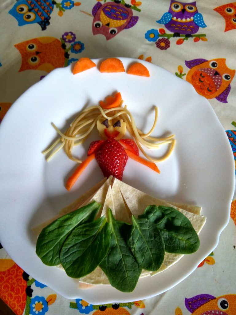 dama elegante. Figura de comida creativa con tortita de maiz,zanahoria,fresa,platano,espaguetis y espinacas.